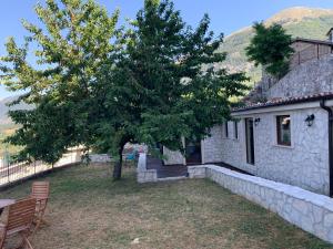 a house with a tree and a table and chairs at Il giardino di Lallo in Barrea