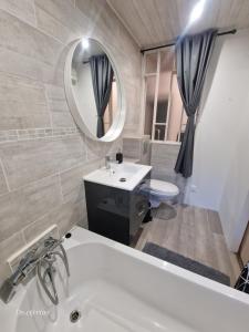 a bathroom with a tub and a sink and a mirror at Gîte climatisé "Baugallo Accordailles" in Saint-Montan +23 photos