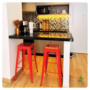 a counter with two red stools in a kitchen at The Quiet Creative, Corporate-Ready 1BR in Tatu City