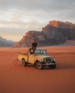 a man sitting on top of a jeep in the desert at Magic rum hussen Luxury in Wadi Rum