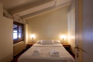 una camera da letto con un letto su cui sono appoggiate due pantofole bianche di Hotel Posta R.T.A. a Madonna di Campiglio Altre 100 foto