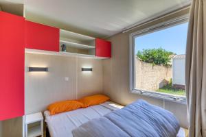 a small bedroom with a bed and a window at Location Mobile home in Marseillan