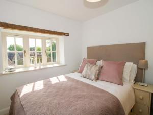 a bedroom with a bed with pink and white pillows at 5 Shrewsbury Road in Much Wenlock