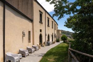 a row of white chairs sitting next to a building at La Locanda degli Amici in Santa Teresa di Riva