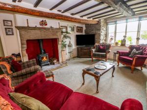a living room with red furniture and a fireplace at Bargate Cottage in Castleton