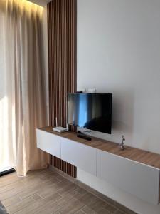 a living room with a flat screen tv on a white wall at Palmera Escape Radhime in Vlorë