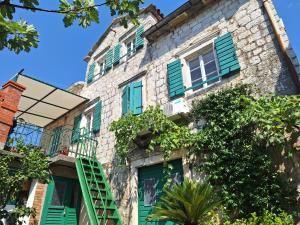 an old stone building with green shuttered windows at Apartments Subotic in Risan