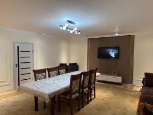 a dining room with a table and a flat screen tv at Apartment Registon in Samarkand