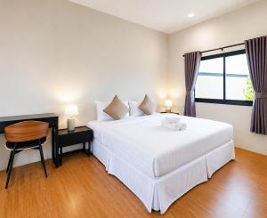 a bedroom with a white bed and a table and a window at Ranong Adventure Resort & Park in Ranong