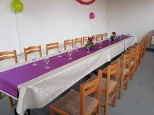 a long table with wine glasses and wooden chairs at Levendula Vendégház - Bezi in Bezi