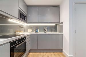 a kitchen with white cabinets and a sink at Modern 1Bed Flat in Ealing Near Tube & Shops in Ealing