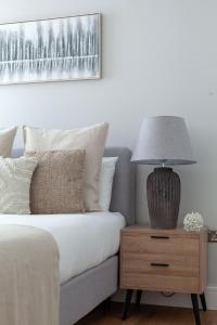 a bed with a nightstand with a lamp on it at Modern 1Bed Flat in Ealing Near Tube & Shops in Ealing +19 photos