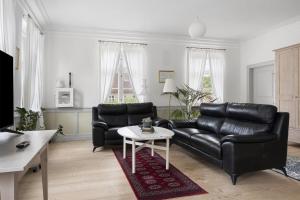 a living room with a black leather couch and a table at Brodremenighedens Hotel, BW Signature Collection in Christiansfeld