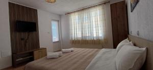 a bedroom with a bed with white pillows and a television at Вила Багрянови in Dospat