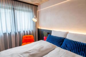 a bedroom with a bed and an orange chair at Savoy Hotel in Frankfurt +3 photos