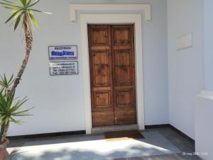 a wooden door in a white room with a palm tree at Marina Azzurra VistaMare - HiTuscany in Marina di Campo