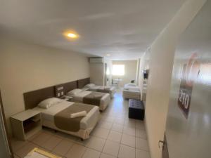 a hotel room with two beds and a hallway at Hotel Central Caruaru in Caruaru