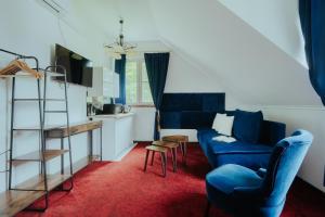 a living room with a blue couch and a kitchen at Dwór Ujazdowski in Nielisz