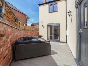 a couch sitting on a patio next to a brick wall at Naseby House in Alfreton