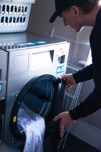 a man is looking into a washing machine at The Dawson Hostel Galway in Galway