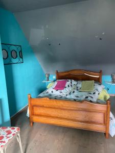 a wooden bed in a room with a blue wall at Maison Entre Terre et Mer in Primelin