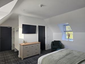 a bedroom with a bed and a tv and a chair at Woodside House in Crook of Alves