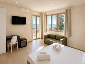 a room with a bed and a couch and a television at Villa Cliff in Aspra