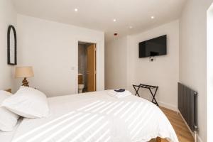 a bedroom with a white bed with a tv on the wall at 6 En-Suites with 7 Beds Near Arena & City in Nottingham