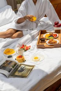 a woman sitting on a bed with a tray of food at Padma Villa - Mountain Estate in Manali in Manāli +40 photos