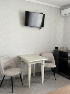 a white table with two chairs and a television on a wall at Euro Hotel Hostel in Kovel +4 photos