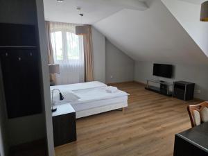 a bedroom with a white bed and a television at Potocki Dwór in Jędrzejów