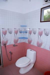 a pink bathroom with a toilet and a pink wall at MarariBeachLaVista1 in Alleppey