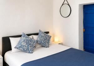 a bedroom with a blue door and a bed with pillows at Garden Residence Andros with Sea View & Pool in Gavrio