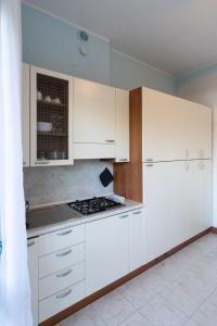 a kitchen with white cabinets and a stove top oven at Casa Gelsomina in Isola Bacucco