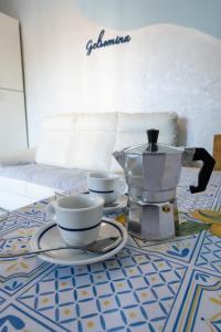 a table with a coffee pot and cups on it at Casa Gelsomina in Isola Bacucco