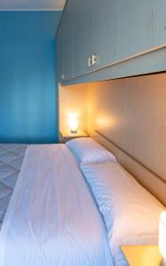 a large white bed in a room with a blue wall at Casa Gelsomina in Isola Bacucco +15 photos