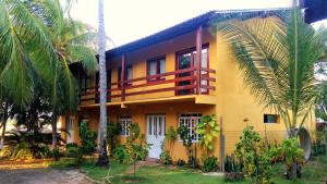 a yellow house with palm trees in front of it at Sossego de Jaua in Camaçari