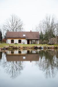 una casa se refleja en el agua de un lago en Atpūtas Vieta Raudiņi, en Kaltene