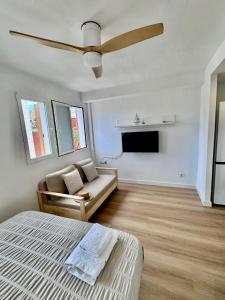 a bedroom with a bed and a couch and a ceiling fan at Mediterráneo Suites Port in Jávea