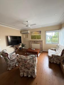 a living room with two chairs and a tv at Ferguson House in Cessnock