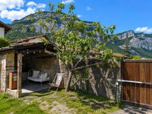 a stone building with a wooden fence and a chair at Le Petit Chalet in Crolles