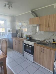 a kitchen with wooden cabinets and a stove top oven at Vormsi Ohvitseride maja korter nr 6 in Hullo