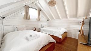 two beds in a room with white walls and wood floors at Bacana Bungalows in Uluwatu