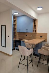 a kitchen with blue cabinets and a wooden table and chairs at Stan Kumbor sa dvije spavace sobe in Kumbor