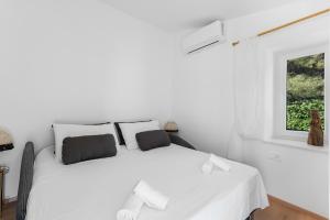 a white bed in a white room with a window at Charming Casa Piccola in Draga Bašćanska