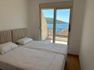 a bedroom with two beds and a view of the ocean at Stan Kumbor sa dvije spavace sobe in Kumbor +2 photos