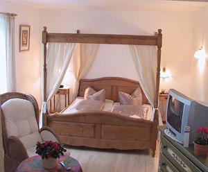 a bedroom with a canopy bed with a television at Hotel Zur Erholung in Braunlage