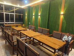 a man sitting at tables in a room with green walls at Ganga Nature Nest in Hawālbāgh