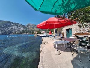 a table with a red umbrella next to the water at Apartments Subotic in Risan +27 photos