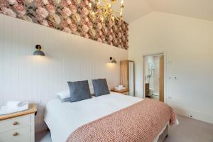 a bedroom with a large white bed with blue pillows at Gardener's Cottage in Alnwick